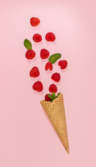 Waffle cone with fallen raspberry on the pink. Summer concept.