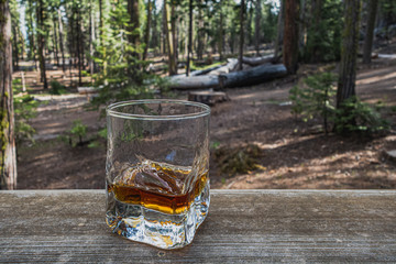 Poured whiskey in a glass surrounded by wooden area. Bourbon neat on a wood ledge.