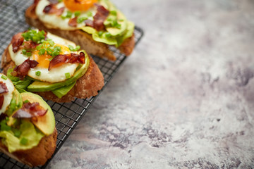 Breakfast concept. Tasty delicious homemade toasts with fried egg, bacon, avocado, lettuce and chive