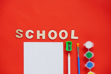 Study flatlay concept. Education supplies -pencil, pen, brush, white paper for notes school and paint on red background, back to school or kindergarten. summertime, creativity and learn background.