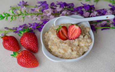Oatmeal with strawberries in a white plate with a spoon. Lunch. Healthy food. Healthy lifestyle. Close-up