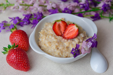 Oatmeal with strawberries in a white plate with a spoon. Lunch. Healthy food. Healthy lifestyle. Close-up