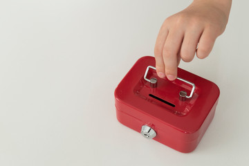 accumulate for poor people or investment. Coins,hand and red moneybox on the white background for charity foundation concept.child throwing money into piggy bank.