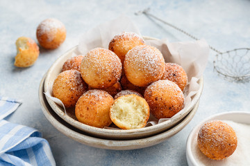 Cottage cheese donuts balls with powdered sugar in a bowl on a blue background. Healthy curd...