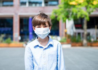 A boy wearing a medical mask at the city center park 