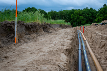 Baustelle mit Rohre im Tiefbau im Baugebiet. Versorgung für Gas, Lichtwellenleiter, Glasfaser,...