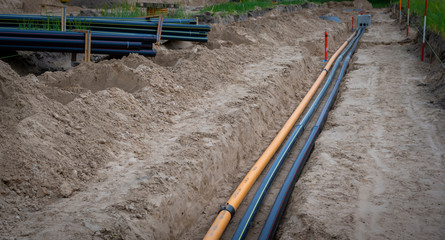 Baustelle mit Rohre im Tiefbau im Baugebiet. Versorgung für Gas, Lichtwellenleiter, Glasfaser,...