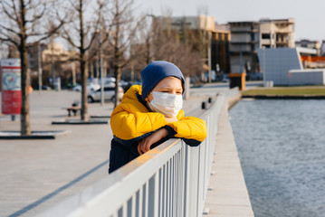 A boy stands on a gray background in a mask during a quarantine with free space. Quarantine in the mask