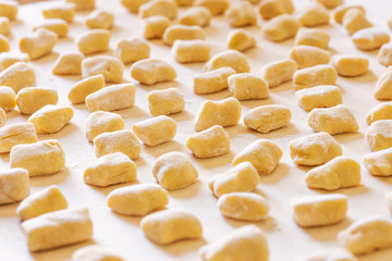 Expanse of homemade gnocchi on a wooden board. These dumplings are made with flour, potatoes and eggs. Gnocchi are a variety of pasta very popular in italy. Concept for cooking at home and handmade.