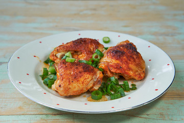 Close up Picture on vintage plate with traditional czech style roasted tasty and spicy chicken legs sprinkler with chopped fresh spring onion. Delicious balanced low calorie food full of nutritions.