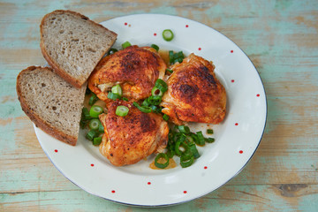 Top view on the vintage plate with marinated and grilled chicken leg pieces and two slices of rustic bread. Juicy and tasty spicy appetizer with balaned nutritions, rich in proteins ideal for parties.