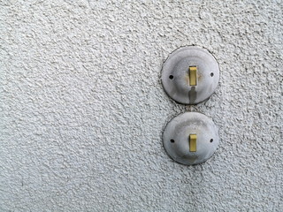 Alte runde Lichtschalter im Stil der Fünfzigerjahre auf ergrautem Rauputz eines Wohnhaus in...