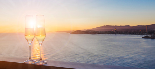 Two glasses with champagne over sunset sea , Summer background