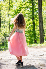 young woman walking in the park in a pink dress
