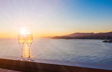 Two glasses with champagne over sunset sea , Summer background