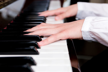 Fototapeta na wymiar a schoolgirl in a white shirt plays the piano keys. selective focus
