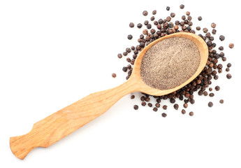 Ground black pepper in a spoon and peppercorns on a white background isolated. The view from top