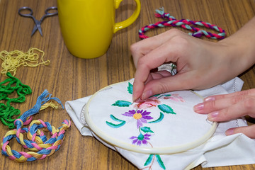 Female hand embroidered cross on the canvas.