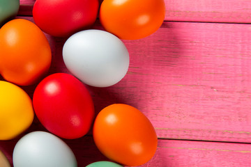 Top view of multicolored Easter eggs on rose background.