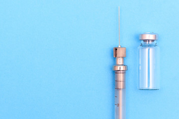 antique syringe made of metal and glass and phial on a blue background. free space for text. copyspace
