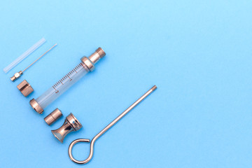 antique syringe disassembled into details on a blue background