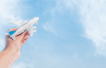 Man hand holding airplane model over sea background dreams of journey in vacation.
