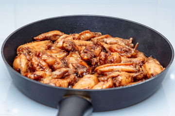 lots of fried chicken wings in a pan on a white ceramic plate. close up