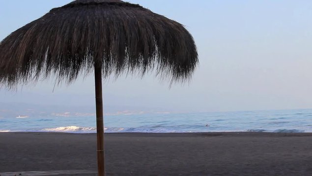 Sombrilla de paja en la playa al atardecer 