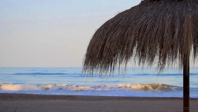 Sombrilla de paja en la playa al atardecer 