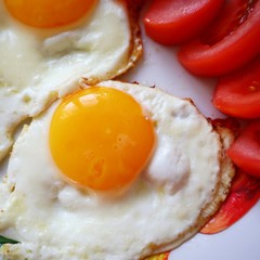 Breakfast food fried eggs with tomatoes on a plate