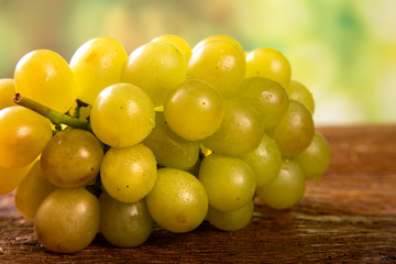 Bunch of green grapes, fruits of autumn, a symbol of abundance on rustic wood background.