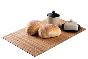 Homemade bread on mat with butter dish on isolated white background