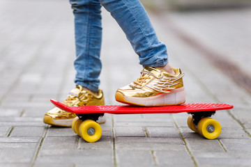 Child's feet in sneakers close-up on a skateboard. Summer sports Hobbies.