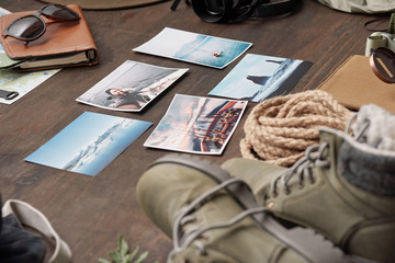 Close-up of adventure photos symbolizing best memories from vacations placed on wooden table with hiking stuff