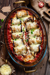 overhead shot of baked eggplant rolls in tomato sauce with melted cheese on top on rustic table