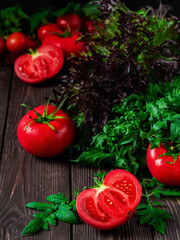 Slice of tomato and ripe red tomatoes close-up on a dark rustic background. Ripe vegetables from the market, ingredients for the preparation of salads or dishes.