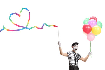 Pantomime man holding a ribbon with a heart shape and a bunch of colorful balloons