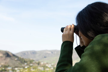 woman looks through the binoculars in mountain