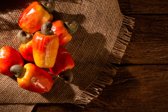 cashew fruit over a  wooden surface.