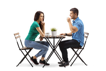 Young man and woman sitting a table and drinking coffee - Powered by Adobe