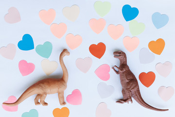 Two dinosaurs on the background of colorful hearts. Concept of Valentine's Day.
