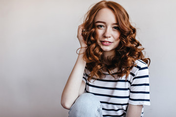 Romantic european woman with shiny ginger hair smiling to camera. Indoor photo of carefree pleased girl expressing happiness.