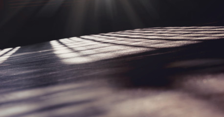 sunlight falling through window jalousie on sports hall dark wooden floor