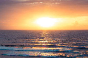 Sea beach surf waves Bali beach Uluwatu surfing spot sunset landscape with cliff view on sea horizon with sun and orange sky as tropical island background