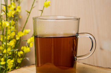 close-up of glass with hot tea and yellow flowers
