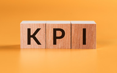 KPI Word Written In Wooden Blocks on Yellow Background