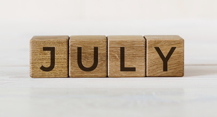 The word July on wooden cubes. Concept Month of year.