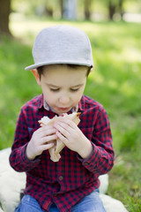 Toddler boy eats sandwich outdoor