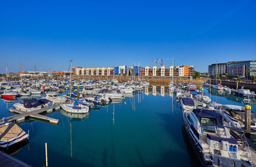 Fototapeta na wymiar Image of St Helier Marina North section from the East marina wall early morning with blue skys and sunshine. Jersey, Channel Islands, UK