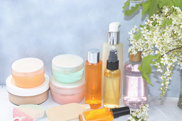 Spa ingredients, a set of cosmetic oils and creams for skin and body care on a gray background with branches of blooming cherry. Shopping concept and modern woman, sale, selective focus